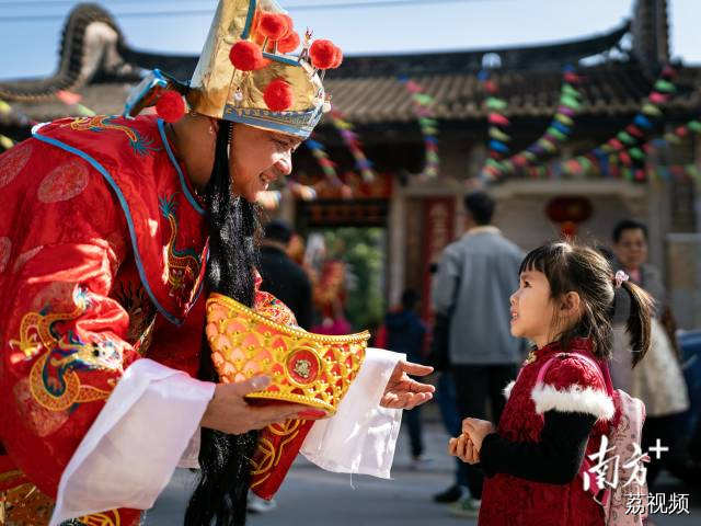 2月11日，大年初二早上，中山市一古村落里，“财神爷”向一名小朋友派喜糖。卓江华 摄